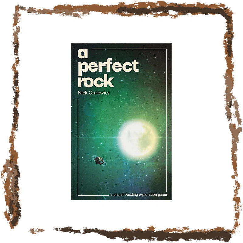 The front cover of the roleplaying game 'A Perfect Rock' by Nick Gralewicz, featuring a green and black space design with a bright glowing planet and a small ringed asteroid. The cover is centered on a white background with a rustic, rusted-brown painted border.
